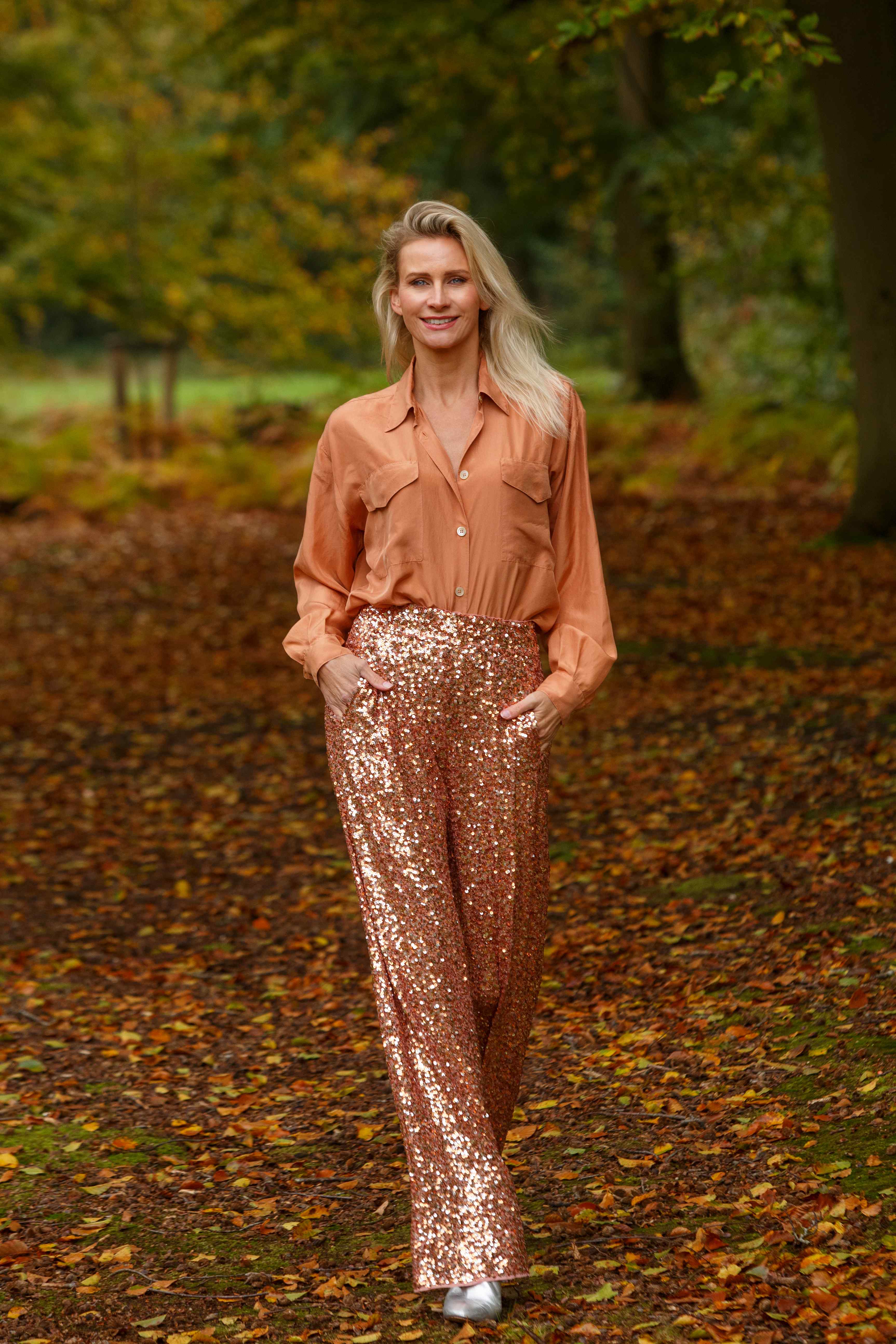 Suzanne Jongerius in een oranje blouse met glitterbroek, rechtop en zelfverzekerd — houding, lijn en uitstraling
