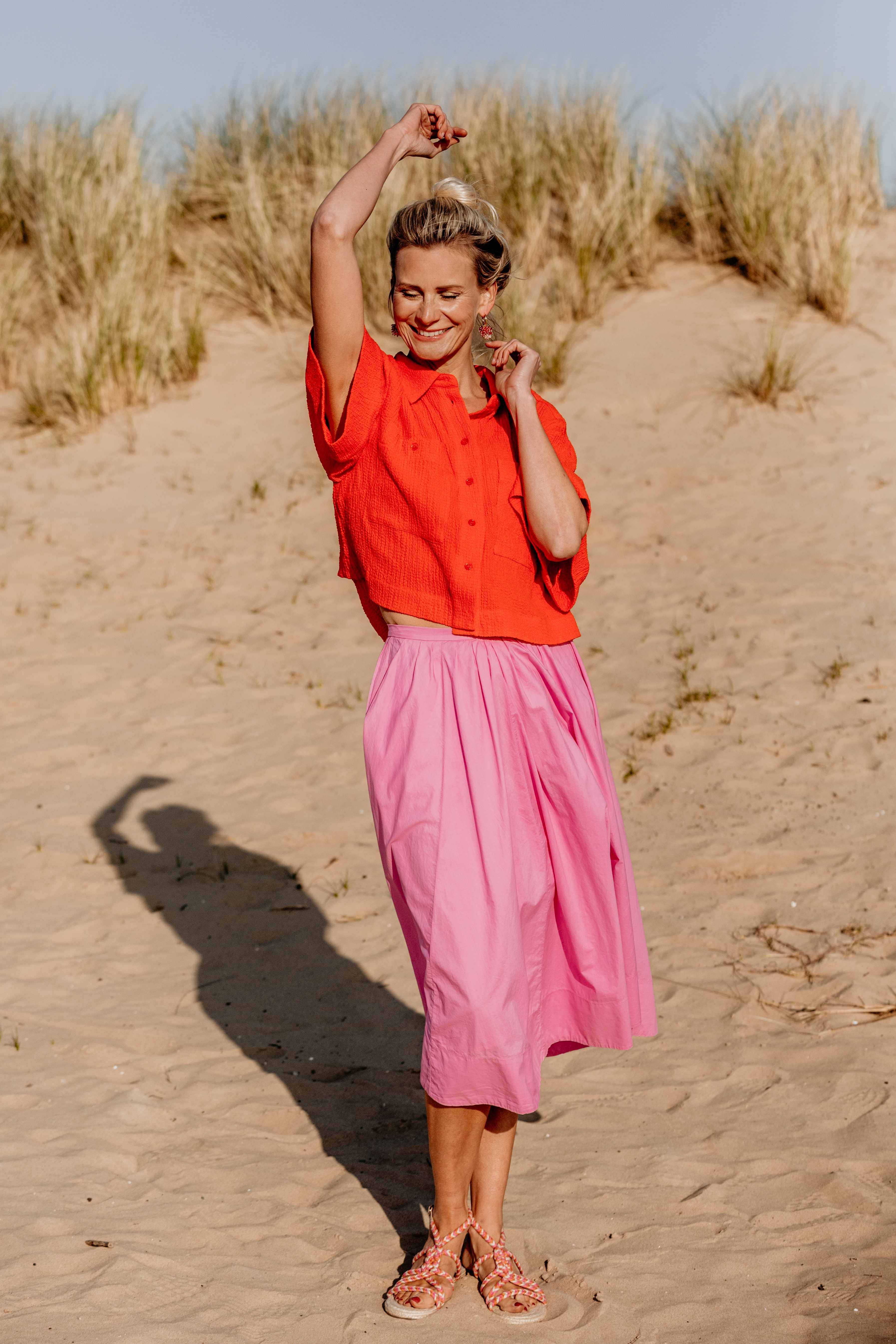 Suzanne danst vrolijk in de duinen met een arm sierlijk omhoog