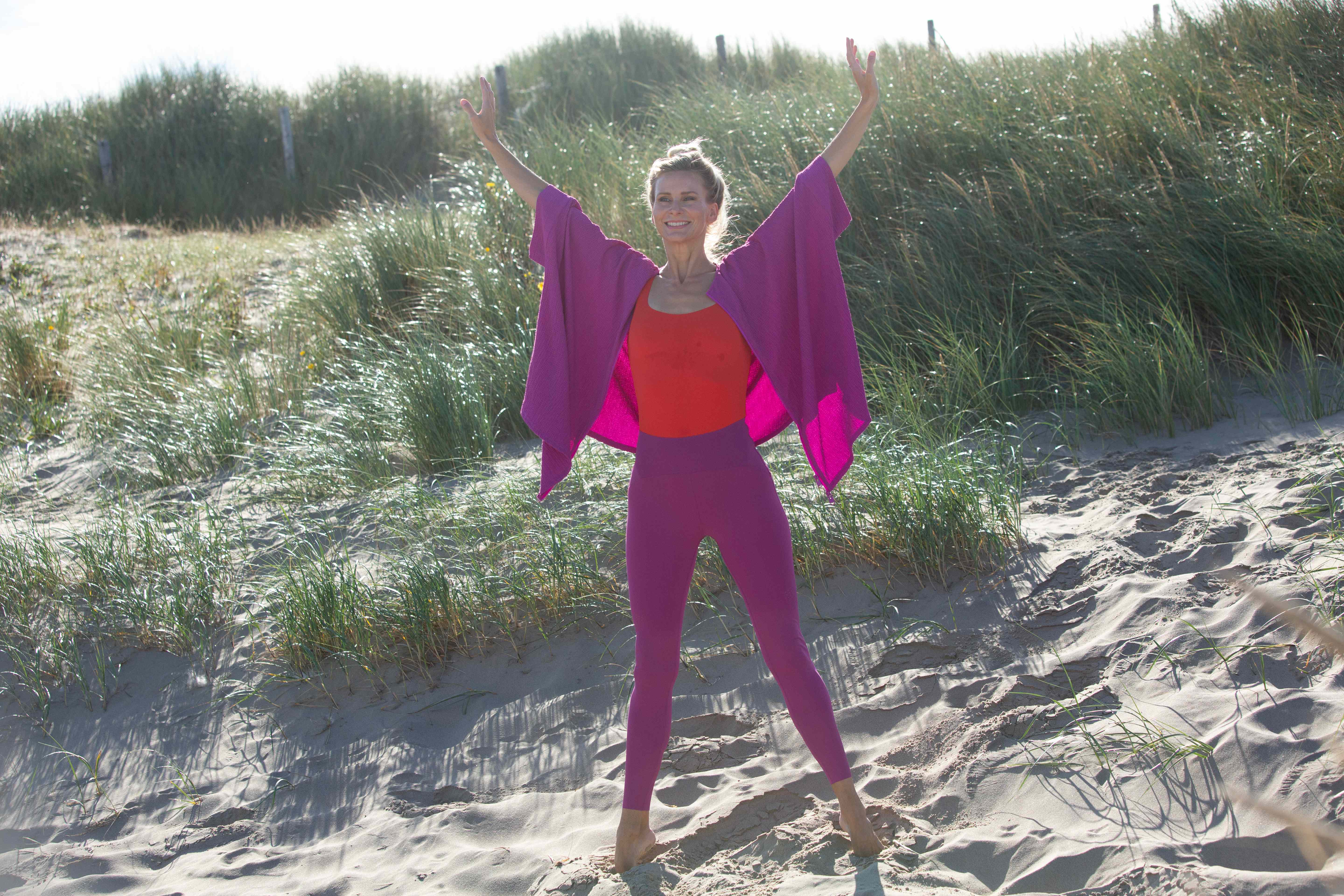 Suzanne met beide armen omhoog in de duinen tijdens Sleek Technique® Ballet Fitness